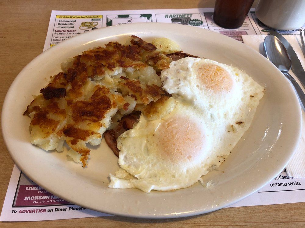Two fried eggs beside crisp home fries on a diner plate